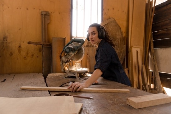 mujer usando ingletadora en taller